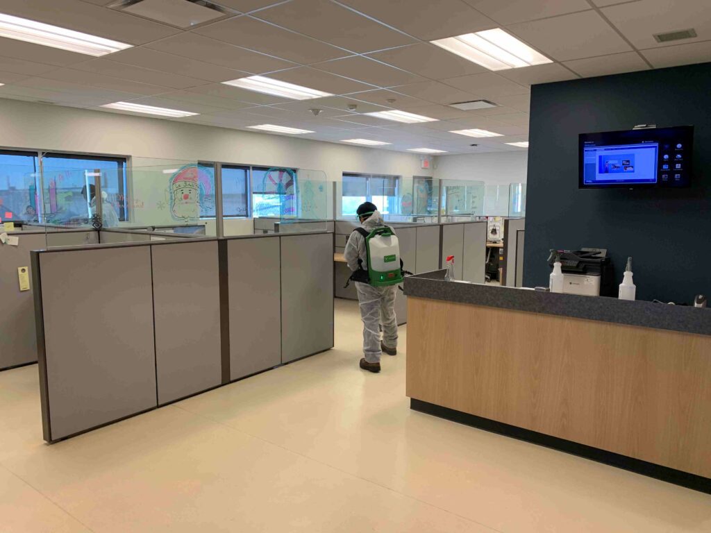 Man with a spraying device sanitizing the cubicle areas