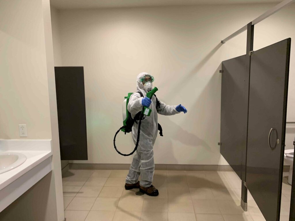 A man in PPE suit sanitizing the comfort room