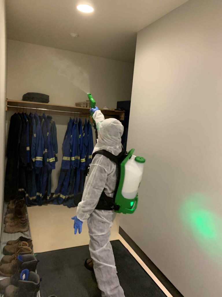 A man in PPE suit cleaning the uniform closet