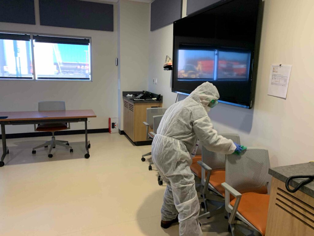 A man in PPE suit cleaning the seats