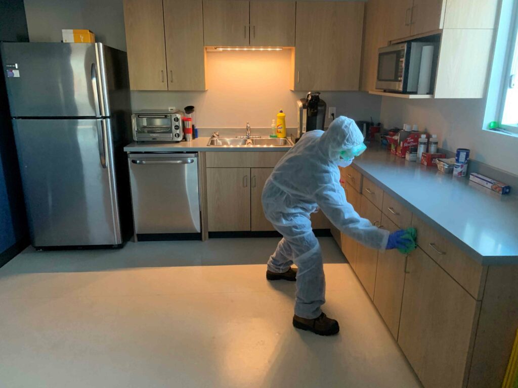 A man in PPE suit cleaning the cabinetry