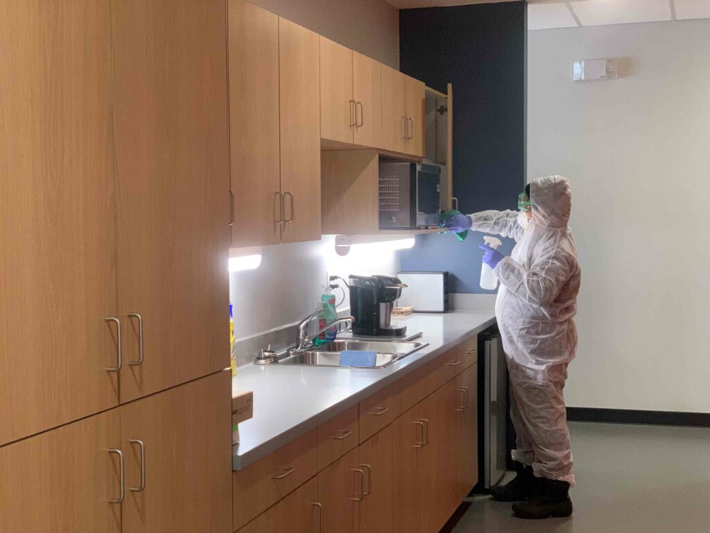 A man in PPE suit cleaning the microwave