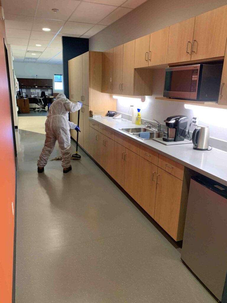 Man in PPE suit mopping the hallway