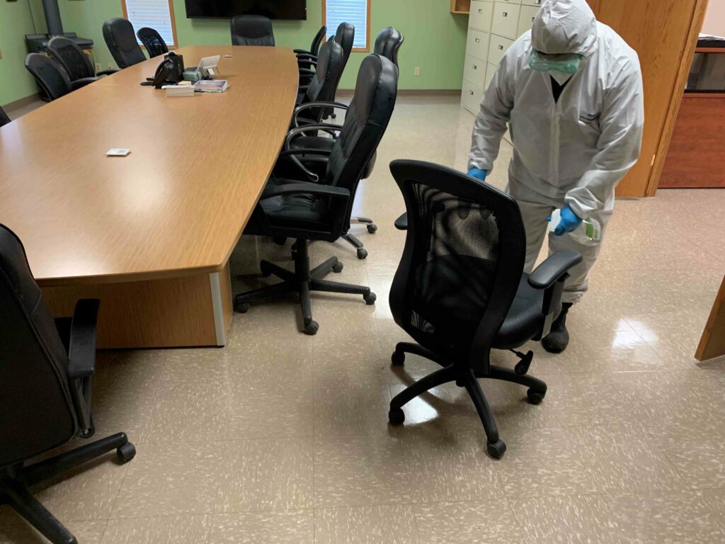 Man in PPE sanitizing the chairs